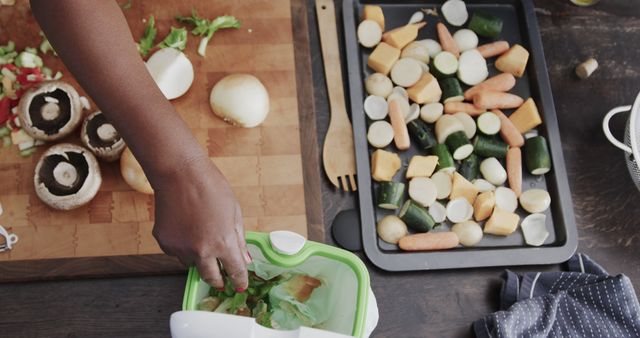 Image shows hands preparing ingredients for a healthy meal. Vegetables like carrots, zucchini, onions, and mushrooms are being chopped on a wooden board and placed on a baking tray. Image can be used for content related to healthy eating, food preparation tutorials, and kitchen organization tips.