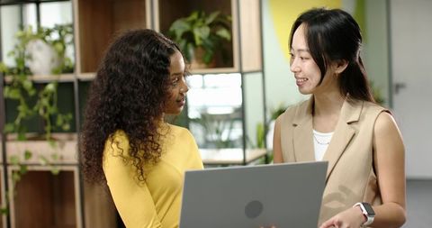Diverse Coworkers Collaborating in Modern Workspace with Laptop