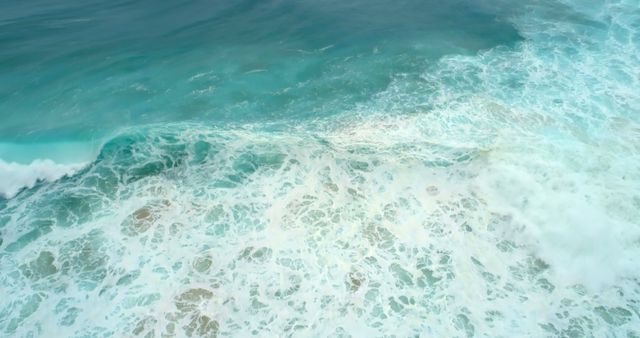 Aerial view of ocean waves crashing, with copy space. Captures the serene yet powerful nature of the sea.