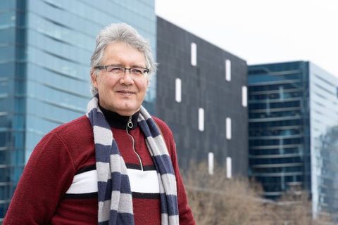 Senior man standing in business district wearing maroon sweater striped scarf and glasses