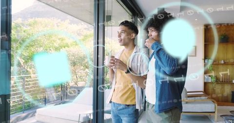 Friends exploring augmented reality interface while sipping coffee on modern balcony