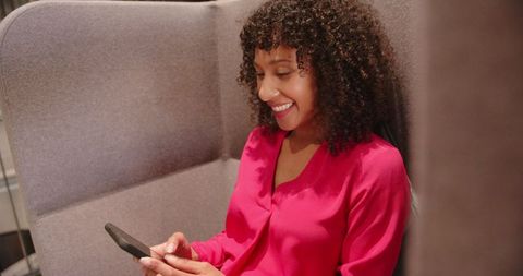 African American Woman Relaxing in Office Lounge with Smartphone