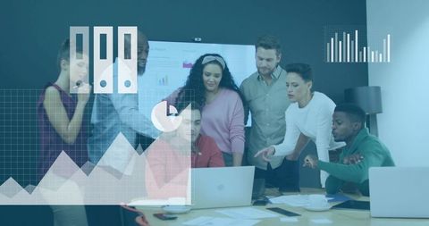 Diverse team collaborating around laptop reviewing business data and charts in boardroom