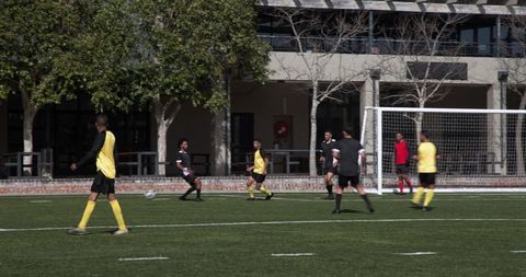 Soccer players on field engaged in team strategy under sun