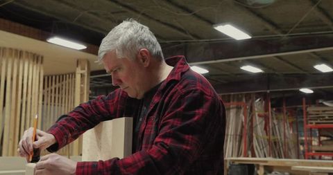 Skilled Carpenter Marking Wood with Precision in Workshop