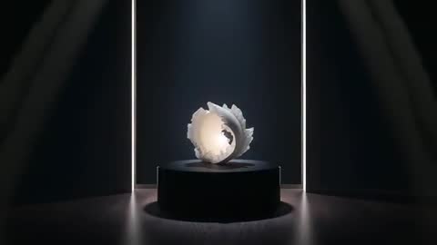 Rotating illuminated ceramic shell sculpture revealing hollow core on dark pedestal