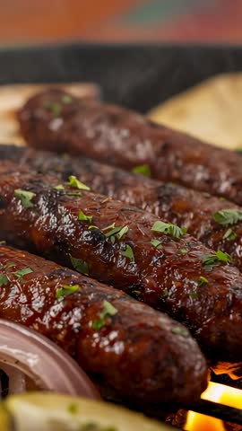 Vertical video grilling kebabs close-up, glossy kebabs charring, parsley sprinkling