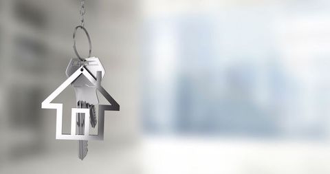 House-Shaped Keychain with Keys Over Blurred Cityscape