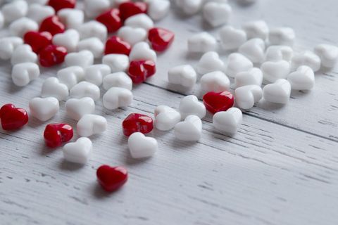 White and red heart-shaped candies on wooden surface