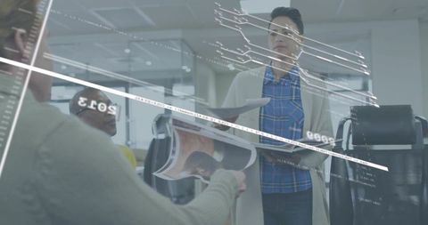 Businesswoman receiving brochure from colleague in modern open-plan office teamwork scene
