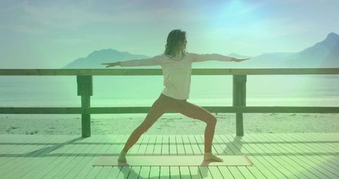 Woman Practicing Yoga Outdoors on Seaside Deck at Sunrise