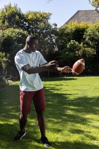 Man Catching Football on Sunny Day in Backyard