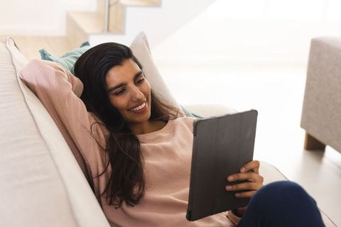 Relaxed Woman Reclining on Sofa with Tablet at Home