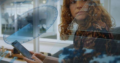 Curly-haired professional using tablet with holographic interface in open-plan office