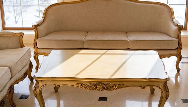 Sunlit beige french sofa and marble coffee table casting warm shadows in elegant living room