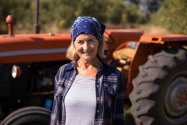 Portrait of happy woman standing against tractor in olive farm on a sunny day
