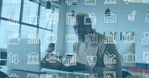 Working Black businessman analyzing finances on laptop with fintech icons overlay