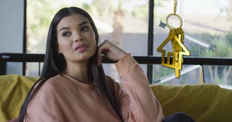 Woman relaxing at home with key symbolizing homeownership