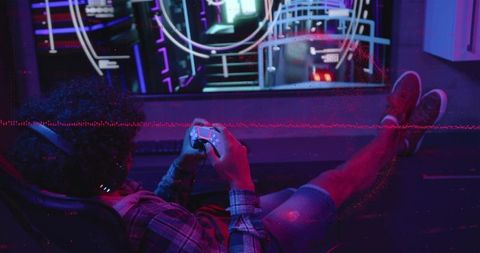 Reclining gamer holding controller in neon-lit room with hud display, headset, casual