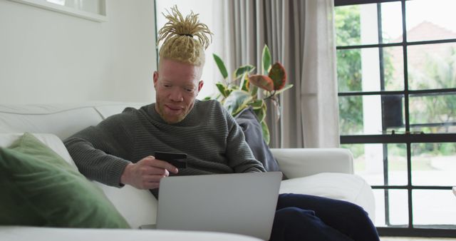 Albino african american man with dreadlocks using laptop. leisure time, using technology, relaxing at home.