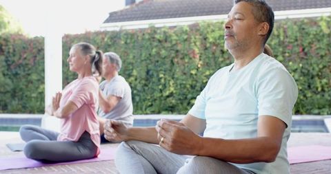 Diverse Group Meditating Outdoors on Yoga Mats by a Pool