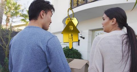 Couple moving into new home with golden house key concept