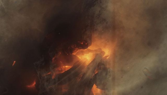 Glowing embers and smoke over burning wooden logs