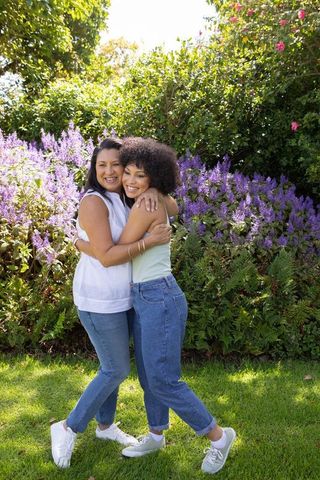 Happy Mother and Daughter Embrace in Vibrant Backyard Garden