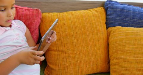 Young Girl Relaxing with Tablet on Colorful Cushions