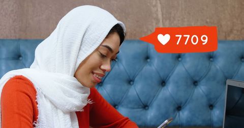 Tech-Savvy Woman in Hijab Engaging on Social Media with Smartphones