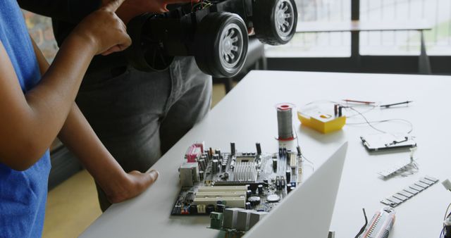 This image depicts students actively working on an electronics project, engaging with circuit boards and robotic components. It is suitable for education-themed materials, articles on STEM education, technology workshops, and advertisements for learning kits.