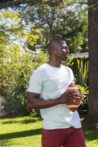 Athletic Man Holding Football on Sunny Lawn