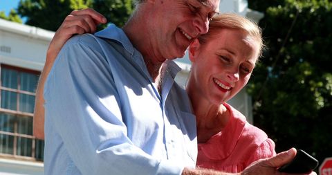 Joyful Senior Couple Enjoying Technology Outdoor on Sunny Day