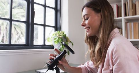 Woman at desk adjusting microphone in bright home office