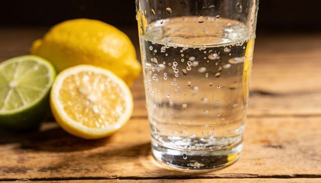 Effervescent sparkling water with lemon and lime on rustic wood table for refreshment