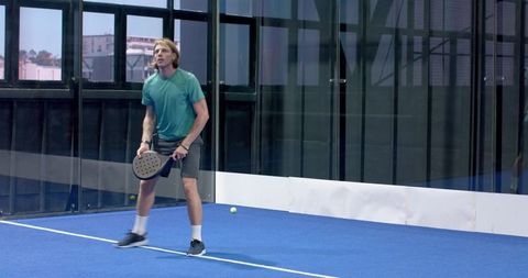 Young man on padel court ready to compete indoors