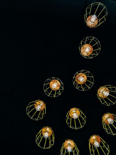 Stock image of hanging industrial cage lights against a black backdrop, highlighting their modern design and geometric shape. Ideal for use in home decor inspiration articles, interior design magazines, architecture blogs, lighting company advertisements, or promotional materials showcasing innovative lighting solutions.