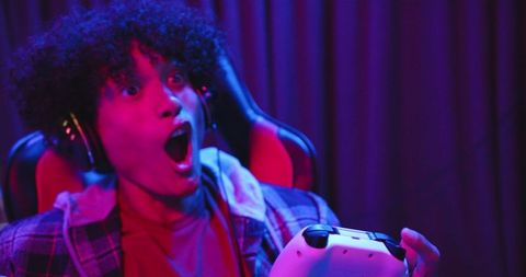 Excited gamer using controller with headphones at night