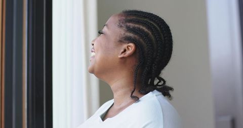 Mid adult african american woman laughing and looking out window with soft daylight