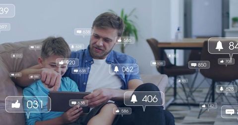 Father and son exploring tablet with social notifications and like bubbles at home