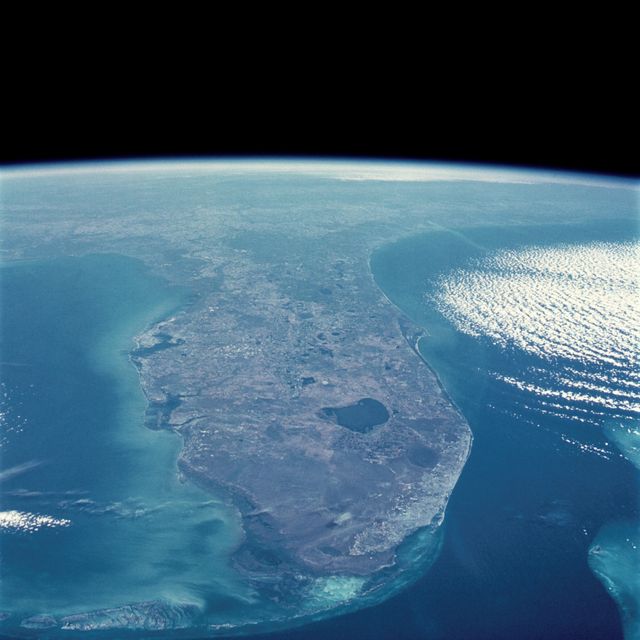 This striking image captures an oblique view of the Florida Peninsula as seen from the Space Shuttle Discovery during one of its missions in January 1985. Clearly visible are the prominent geographical features including the Atlantic Coast and the Gulf of Mexico. Cape Canaveral, home to Kennedy Space Center, can be seen jutting out into the Atlantic. Perfect for educational materials, scientific studies, and presentations on geography or space exploration.