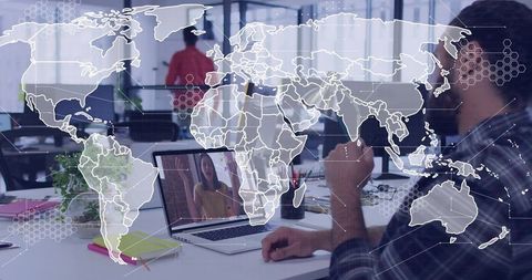 Man gesturing during video call with woman on laptop in open office with global overlay