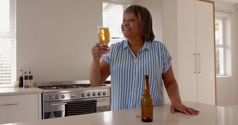 Senior Woman Enjoying Refreshing Beverage in Modern Kitchen