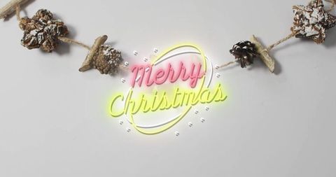 Neon merry christmas script with rustic pinecone garland on minimal gray background