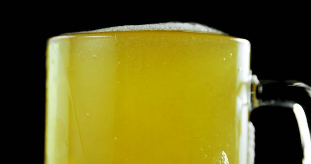 Perfect for illustrating beer-related articles, visual content for bars and pubs, or advertisements highlighting refreshing beverages. The close-up captures the foam and refreshing look of beer, making it ideal for marketing materials focusing on drinks.