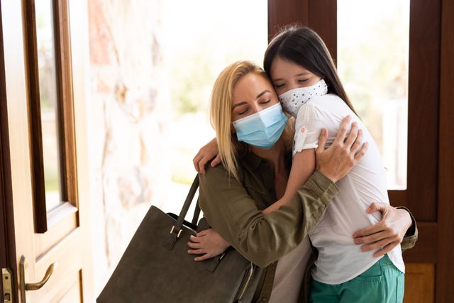 Mother and Daughter Hugging with Facemasks at Home - Download Free Stock Photos Pikwizard.com