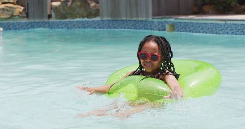 Afro girl enjoying pool fun with green inflatable ring