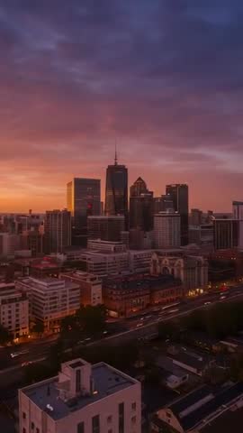 Vertical city skyline dimming into sunset over downtown highrises with light trails