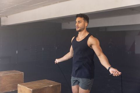 Athletic man jumping rope in urban warehouse gym setting