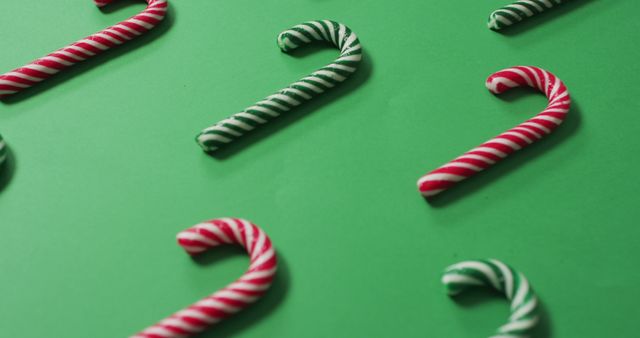 Horizontal candy canes with red and white stripes adorning a green background create a festive feel. Perfect for holiday-themed projects such as greeting cards, Christmas advertisements, party invitations, or decorative wallpapers.